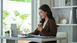 © wattana - Confident female entrepreneur drinking coffee and using laptop at comfortable workplace.