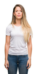 Wall Mural - Beautiful young woman wearing t-shirt and jeans with a confident expression on smart face thinking serious