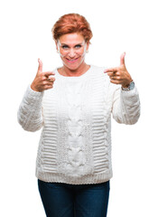 Poster - Atrractive senior caucasian redhead woman wearing winter sweater over isolated background pointing fingers to camera with happy and funny face. Good energy and vibes.