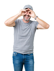 Wall Mural - Handsome middle age hoary senior man wearing sport cap over isolated background doing ok gesture like binoculars sticking tongue out, eyes looking through fingers. Crazy expression.