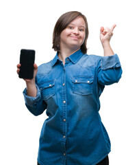 Wall Mural - Young adult woman with down syndrome showing smartphone screen over isolated background very happy pointing with hand and finger to the side