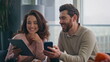 © stockbusters - Cheerful couple watching gadgets having fun with social media at kitchen closeup