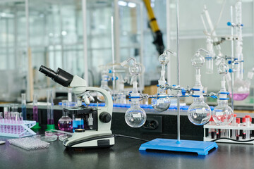 Poster - Microscope, set of glassware and other laboratory supplies necessary for scientific experiments standing on workplace of chemist