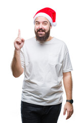 Poster - Young caucasian hipster man wearing christmas hat over isolated background pointing finger up with successful idea. Exited and happy. Number one.