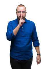 Sticker - Young caucasian hipster man wearing glasses over isolated background asking to be quiet with finger on lips. Silence and secret concept.