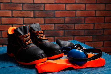 Wall Mural - Pair of working boots, reflective vest and earmuffs on blue wooden surface