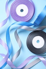 Wall Mural - Ribbon reels in different colors on light blue background, flat lay