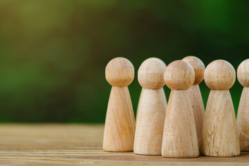 Poster - Group of wooden figurines on a wooden surface, symbolizing teamwork and unity, with a blurred green background, perfect for business and leadership concepts.