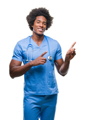 Canvas Print - Afro american surgeon doctor man over isolated background smiling and looking at the camera pointing with two hands and fingers to the side.