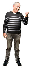 Wall Mural - Handsome senior man wearing winter stripes sweater smiling with happy face looking and pointing to the side with thumb up.