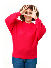 Wall Mural - Beautiful middle ager senior woman red winter sweater over isolated background Doing heart shape with hand and fingers smiling looking through sign