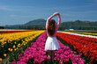 © Oleksandra - Fancy woman enjoying sun in beautiful holland tulip field. Cheerful woman taking off sunhat in summer sunny day. Relaxed girl turning face to sun in spring flower garden. Girl in a tulip field