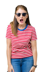 Poster - Middle age mature woman wearing sunglasses over isolated background afraid and shocked with surprise expression, fear and excited face.