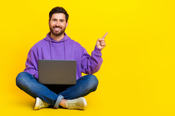 Wall Mural - Full body photo of attractive young man point empty space netbook dressed stylish violet clothes isolated on yellow color background