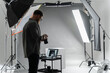 © Big Shot Theory - A photographer in a studio focuses on adjusting camera settings for the perfect shot