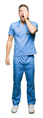 Poster - Handsome doctor man wearing medical uniform over isolated background Yawning tired covering half face, eye and mouth with hand. Face hurts in pain.