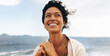 © (JLco) Julia Amaral - Joyful smiling woman with wavy hair enjoying a windy seaside day in close-up portrait
