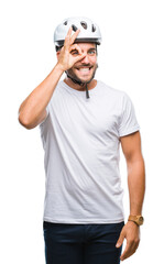 Sticker - Young handsome man wearing cyclist safety helmet over isolated background doing ok gesture with hand smiling, eye looking through fingers with happy face.