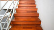 © Pernandi Imanuddin - Close-up view of a modern wooden staircase with a white handrail. The staircase is lit by natural light, creating a bright and clean atmosphere. Wooden Staircase Interior Design