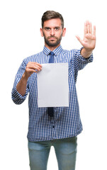 Poster - Young handsome man holding blank paper over isolated background with open hand doing stop sign with serious and confident expression, defense gesture