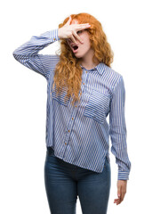 Poster - Young redhead bussines woman peeking in shock covering face and eyes with hand, looking through fingers with embarrassed expression.