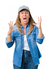 Poster - Beautiful middle age woman wearing sport cap over isolated background crazy and mad shouting and yelling with aggressive expression and arms raised. Frustration concept.