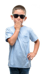 Canvas Print - Dark haired little child wearing sunglasses cover mouth with hand shocked with shame for mistake, expression of fear, scared in silence, secret concept