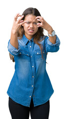 Wall Mural - Young beautiful brunette woman wearing blue denim shirt over isolated background Shouting frustrated with rage, hands trying to strangle, yelling mad