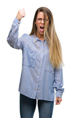 Sticker - Beautiful young woman wearing elegant shirt and glasses angry and mad raising fist frustrated and furious while shouting with anger. Rage and aggressive concept.