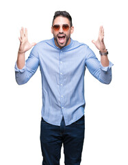 Canvas Print - Young handsome man wearing sunglasses over isolated background celebrating crazy and amazed for success with arms raised and open eyes screaming excited. Winner concept