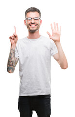 Wall Mural - Young tattooed adult man showing and pointing up with fingers number six while smiling confident and happy.