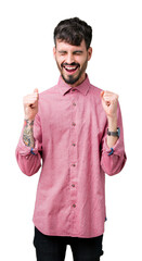 Canvas Print - Young handsome man wearing pink shirt over isolated background excited for success with arms raised celebrating victory smiling. Winner concept.