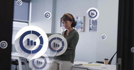 Poster - Image of multiple bar graph icons floating over asian woman using laptop at office