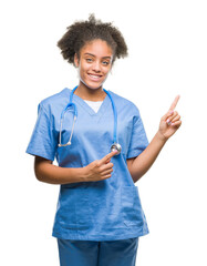 Sticker - Young afro american doctor woman over isolated background smiling and looking at the camera pointing with two hands and fingers to the side.