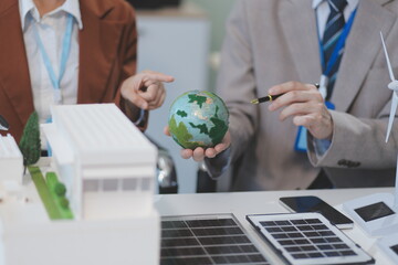 Wall Mural - female alternative energy engineer hold a windmill power sample model and discuss with her male colleague for alternative power in the studio