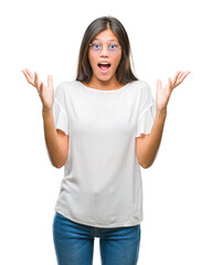 Wall Mural - Young asian woman wearing glasses over isolated background celebrating crazy and amazed for success with arms raised and open eyes screaming excited. Winner concept