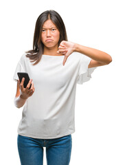 Canvas Print - Young asian woman texting using smartphone over isolated background with angry face, negative sign showing dislike with thumbs down, rejection concept