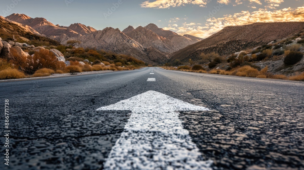 An asphalt road stretches into the distance with a painted white arrow ...