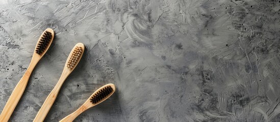 Poster - Bamboo toothbrushes arranged on a gray stone surface with space for text or images, creating a minimalist bath background.