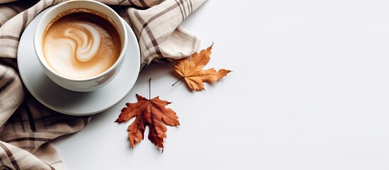 Aufkleber - A cup of coffee sits on a checkered scarf with a fallen leaf against a white background, offering plenty of copy space in the image.