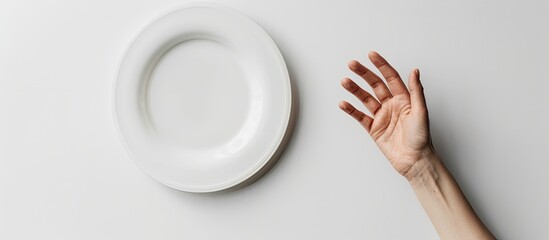 Aufkleber - A food-themed setting with a hand displaying a gesture on a white plate against a white studio backdrop in a top view with copy space image.