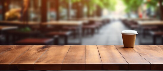 Poster - The central focus is an empty brown wooden table set against a blurred Coffee shop background with bokeh effect for showcasing products in a copy space image.