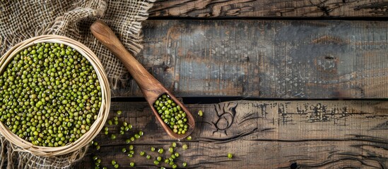 Poster - Top view of a basket containing raw mung beans and a wooden spoon on a wooden background, with copy space image.