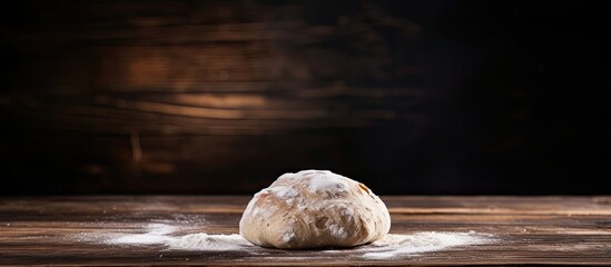 Poster - Dough lump resting on a wooden table with a dark backdrop, showing ample copy space image.