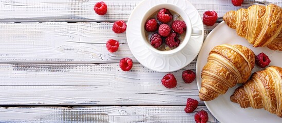 Poster - Croissants paired with coffee and fresh raspberries on a white wooden surface. Background offers room for text in a copy space image.