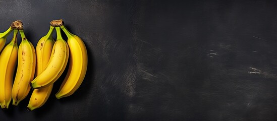 Poster - Aerial perspective showing four bananas on a dark slate surface with copy space image to the right.