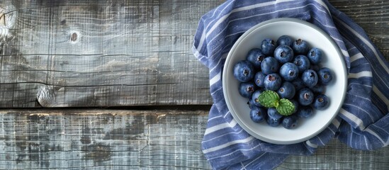 Canvas Print - Blueberries from the forest placed in a white bowl on a blue striped napkin over a gray wooden surface provides a rustic and serene copy space image.