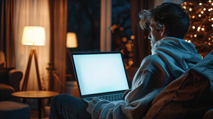 Over shoulder shot of a young man using computer laptop in front of an blank white computer screen in home