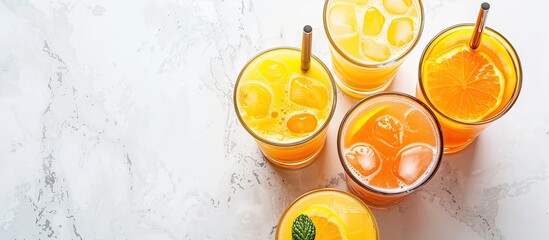 Poster - Summer drink selection of orange, mango, or lemon juice in a tall glass with ice and straws, placed on a white marble surface, seen from above, with room for text in the image.