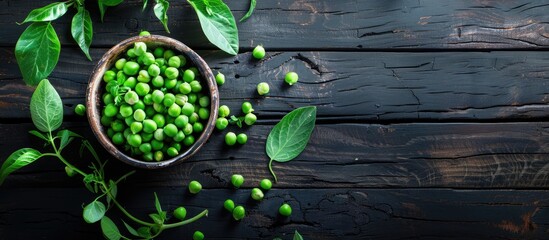 Poster - Top view of fresh organic raw green peas in a bowl with pea plants leaves on a dark wooden table background, ideal for healthy eating, vegan and vegetarian diets, with copy space image.